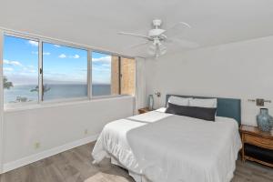 a white bedroom with a bed and a large window at Brand New Condo with excellent reviews in Kahana