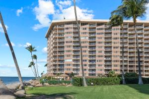 a large building on the beach with palm trees at Brand New Condo with excellent reviews in Kahana