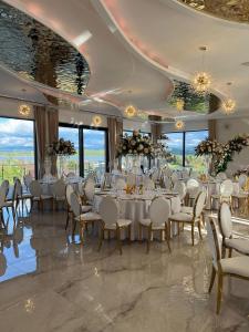 un salón de banquetes con mesas y sillas blancas y ventanas en Złoty Szałas en Zarzecze
