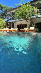 uma piscina com mesas e cadeiras em frente a uma casa em Marygio Gili Resort em Gili Trawangan