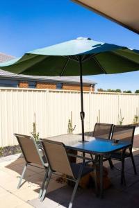 a table and chairs with an umbrella on a patio at Shepparton Family Haven Spacious Retreat in Shepparton