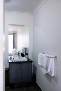 a bathroom with a sink and a mirror and towels at Shepparton Family Haven Spacious Retreat in Shepparton