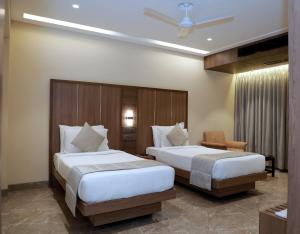 a hotel room with two beds and a chair at HOTEL ARCHANA RESIDENCY in Mumbai