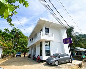 a white building with motorcycles parked in front of it at Lansogo Homestay in Painan +12 photos