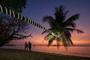 dos personas de pie en una playa con una palmera en GajaPuri Resort Koh Chang, en Ko Chang