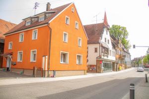 un edificio arancione sul lato di una strada di F&F Suites Ilsfeld - 3 Zimmer OG Apartment - Zentral mit kostenfreien Privatparkplätzen und WLAN a Ilsfeld