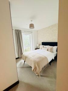 a bedroom with a large bed and a window at Luxurious & Spacious 2 Bed Apartment- Private Parking in Kent