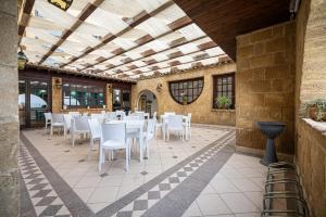 um pátio com mesas e cadeiras brancas num edifício em La Rosa Hotel - Selinunte em Marinella di Selinunte