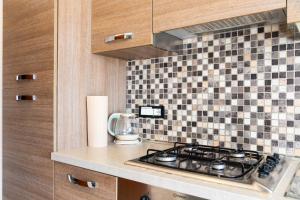 una cucina con piano cottura e una parete piastrellata di Appartamento Il Mare e Dintorni a Portoferraio