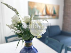 un vaso blu pieno di fiori bianchi su un tavolo di MAYFLOWER terrazza vista mare e posto auto a 50 metri dal mare a Castiglione della Pescaia