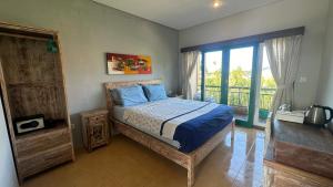 a bedroom with a bed with blue pillows and a balcony at Bukawa Lodge Jimbaran in Jimbaran