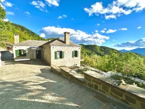 a stone house on a patio with mountains in the background at Waterfall Kataraktis Vatatsi in Vatátsion