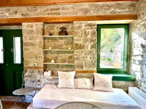 a bedroom with a bed and a stone wall at Waterfall Kataraktis Vatatsi in Vatátsion