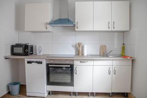una piccola cucina con armadietti bianchi e forno a microonde di F&F Suites Ilsfeld - 3 Zimmer OG Apartment - Zentral mit kostenfreien Privatparkplätzen und WLAN a Ilsfeld