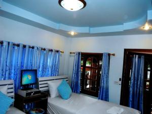 a bedroom with a bed and a tv and blue curtains at Suksomjai Hotel in Rayong