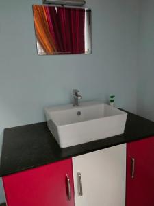 a bathroom with a white sink and red cabinets at Kausthubham home stay, varkala in Varkala