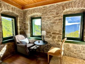 a room with a chair and a table and two windows at Waterfall Kataraktis Vatatsi in Vatátsion