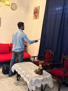 un hombre de pie en una sala de estar sosteniendo una varita en Octave en Agra