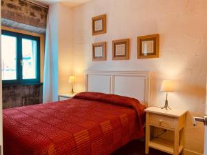 a bedroom with a red bed and two tables with lamps at Apartamentos Rincón del Puerto in San Vicente de la Barquera