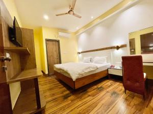 a bedroom with a bed and a television and a chair at Hotel SHIVAM ! Varanasi Forɘigner's Choice ! fully-Air-Conditioned-hotel lift-and-Parking-availability, near Kashi Vishwanath Temple, and Ganga ghat 2 in Varanasi