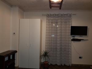 a room with a window with a television and a curtain at Bed and Breakfast MON AMOUR in Flagogna