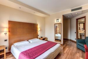 una camera con un grande letto e una sedia blu di Luna Hotel Motel Lago Maggiore Arona a Oleggio Castello