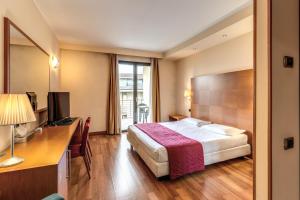 オレッジョ・カステッロにあるLuna Hotel Motel Lago Maggiore Aronaのベッドとデスクが備わるホテルルームです。
