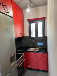 a red kitchen with a sink and a window at Samurai apartments -Catrin- in Koropi