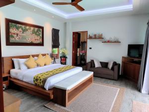 a bedroom with a bed and a couch and a television at Bangtao Boutique Villa in Bang Tao Beach