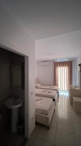 a room with three beds and a sink and a bathroom at Hotel Skura in Librazhd