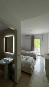 una camera con due letti, lavandino e specchio di Hotel Skura a Librazhd