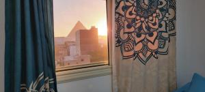 a window with a curtain and a view of the pyramid at Pyramids Temple Guest House in Cairo