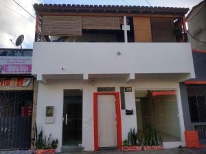 a white building with a red door on a street at Tubarao Branco Suites Central Area in Itacaré