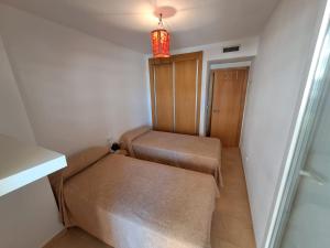 a small room with two beds and a light at Apartamentos Punta Cormorán V.v. in La Manga del Mar Menor