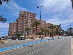 an empty street with palm trees and a tall building at Apartamentos Punta Cormorán V.v. in La Manga del Mar Menor