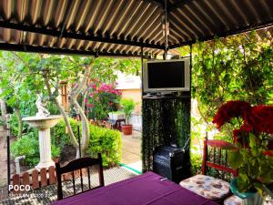 a patio with a table and a television on a pergola at Доли in Pomorie +3 photos