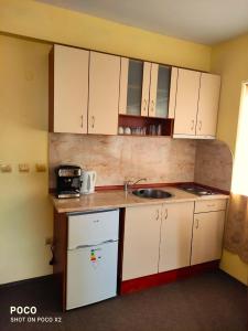 a small kitchen with white cabinets and a sink at Доли in Pomorie