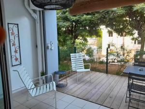a porch with two chairs and a table and a fence at Les aigrettes in Saint-Paul