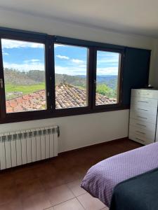 a bedroom with three windows with a view of a roof at Apartamentos La Peral in La Peral