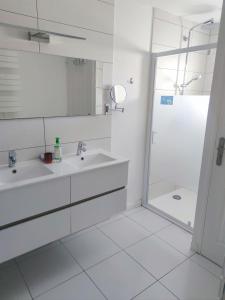 uma casa de banho branca com um chuveiro e um lavatório. em Agréable Maison, toute équipée, proche du lac d'Arjuzanx em Morcenx