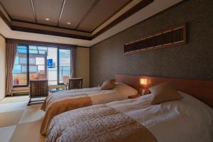 a bedroom with two beds and a large window at Isoaruki no Yuyado Ushiogumo -6 years or older- in Kawazu