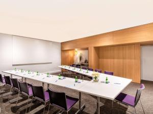 a large conference room with a long table and purple chairs at Novotel Abidjan in Abidjan
