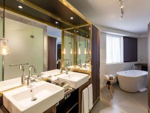 a bathroom with two sinks and a bath tub at INK Hotel Amsterdam - MGallery Collection in Amsterdam