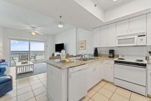 a kitchen with white cabinets and a view of the ocean at Tidewater 503 in Orange Beach