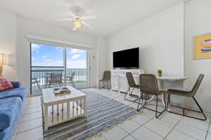 a living room with a couch and a table and a tv at Tidewater 503 in Orange Beach