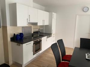 a kitchen with white cabinets and a table with chairs at Haus Lothringen, TOP 8 in Bad Gastein