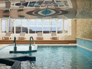 Sofitel Biarritz Le Miramar Thalassa في بياريتز: مسبح في فندق فيه كراسي وسقف