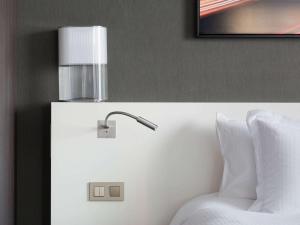 a bed with a lamp on top of a wall at Pullman Paris La Défense in Courbevoie