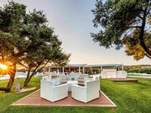 a group of white chairs sitting on a lawn at Almar Timi Ama Resort & Spa in Villasimius