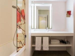 y baño con lavabo, espejo y toallas. en Mercure Bordeaux Centre Ville, en Burdeos